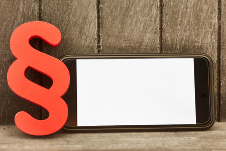 Blank screen on smartphone beside a red paragraph sign as law symbol