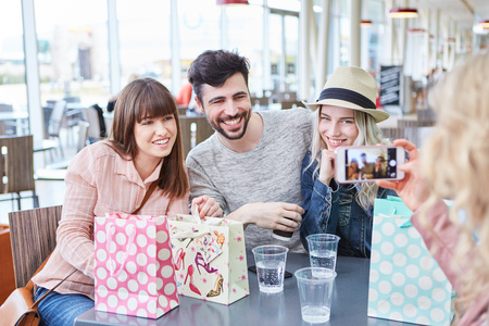 Teenagers as friends can be photographed with the smartphone in the bistroの写真素材