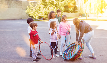 Children in elementary school together do sports on school playground with tires and sports teacherの写真素材