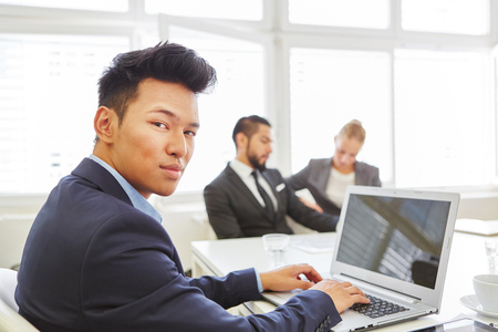 Asian man as competent programmer using laptop computer in the officeの写真素材