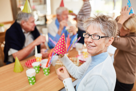 Old woman and seniors friends celebrate birthday party together at retirement homeの写真素材