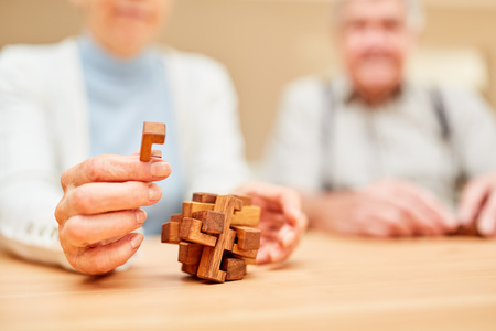 Seniors make a game of patience with a wooden puzzle for concentration and patience