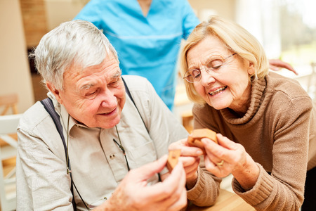 Seniors with dementia play a wood puzzle as employment or therapy