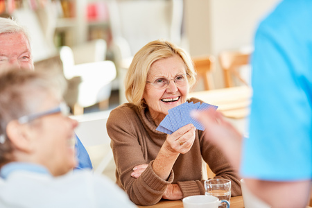 Senior woman has fun playing cards with friends in retirement homeの写真素材