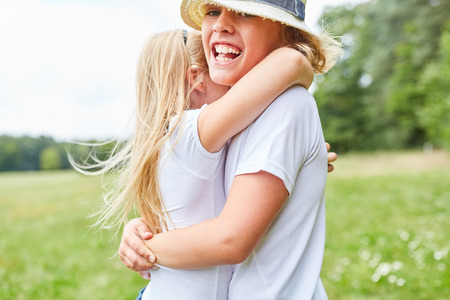 Smiling boy is hugged by sister or girlfriend in the greenの写真素材