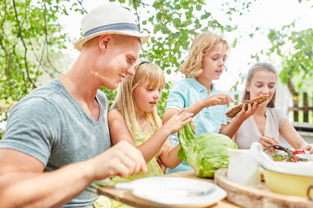 Family and children have breakfast together in the garden in summerの写真素材