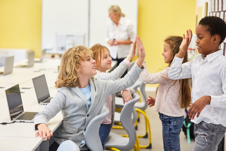 Children in the elementary school elementary school give themselves a high five in the computer...