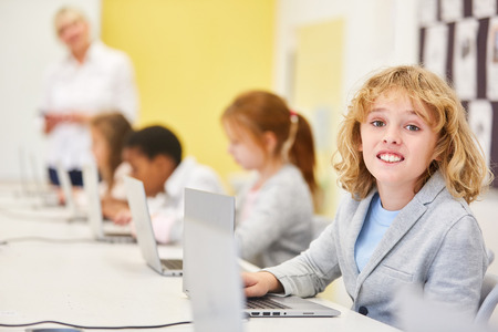 Blond boy as a student in computer teaching a primary school at the laptop