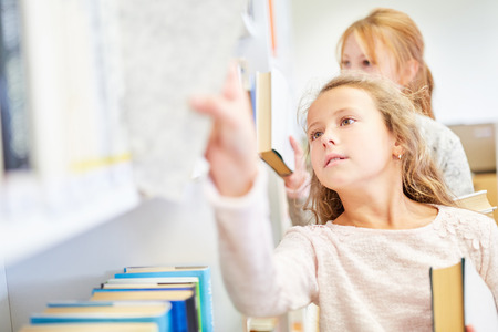 Girls as students in the school's library are researching for a bookの写真素材