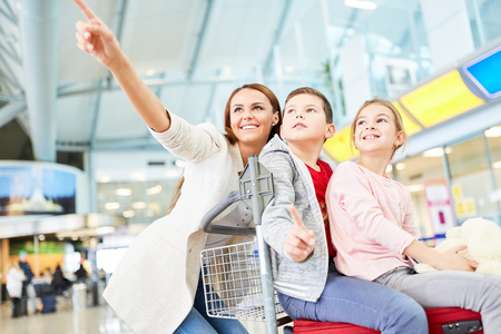 Happy mother and two kids in the airport terminal are looking forward to the air travelの写真素材