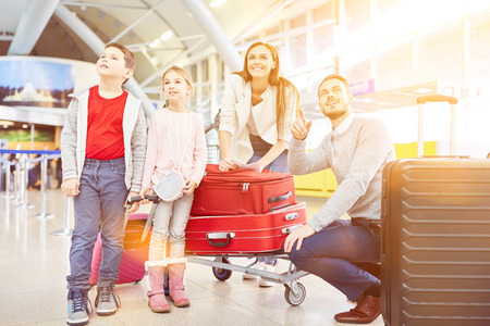 Family with two children and luggage at the airport or train station on vacationの写真素材