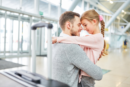 Father and daughter hug each other in greeting after a trip in the airport terminalの写真素材