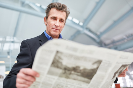 Businessman is reading a daily newspaper before a business trip in the airport or train stationの写真素材