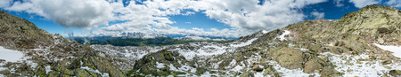 Rocks and snow in the mountains of the French Alps in front of sky with clouds