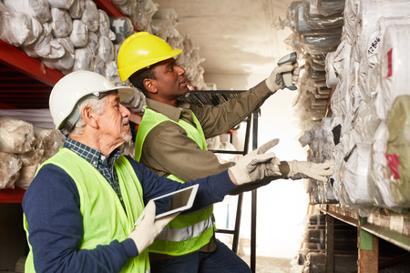 Order picker with tablet pc and young warehouse worker in carpet warehouse