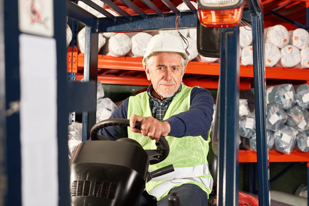 Senior worker on the forklift in a warehouse of a logistics companyの写真素材