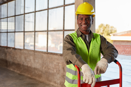 Young man as a logistics apprentice by mail order with a transport cart