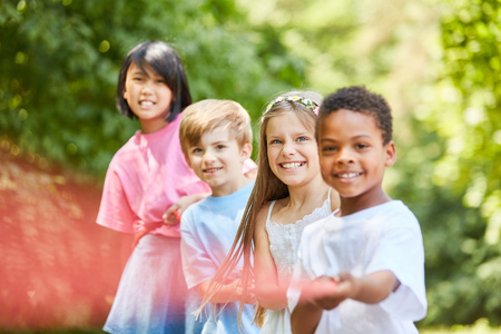 Multicultural group Children in tug of war as a team in natureの写真素材
