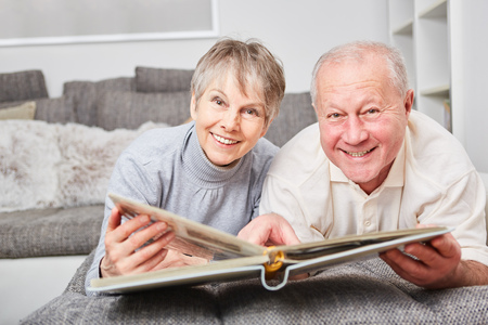 Senior couple looks happy at photo album for leisure
