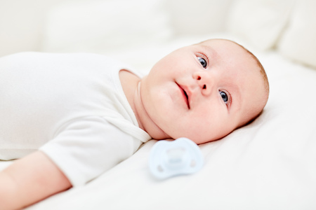 Newborn baby lies on his back and looks curious and alert