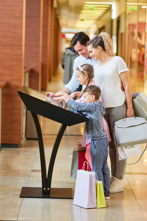 Family learns about the mall on the touchscreen information kioskの写真素材