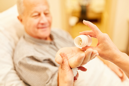 Senior as a patient gets medication from a caregiver in the nursing homeの写真素材