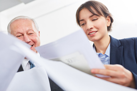 Businesswooman and senior look at contract together in teamworkの写真素材