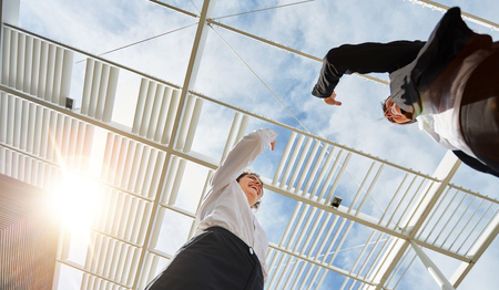 Two successful business women give themselves high five in front of the officeの写真素材