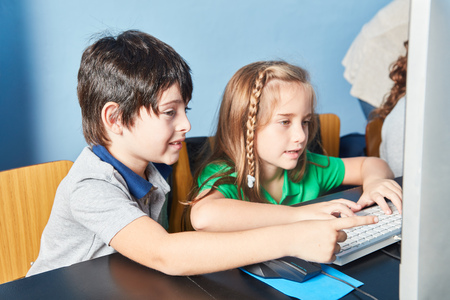 Boy and girl together in computer lessons in elementary schoolの写真素材