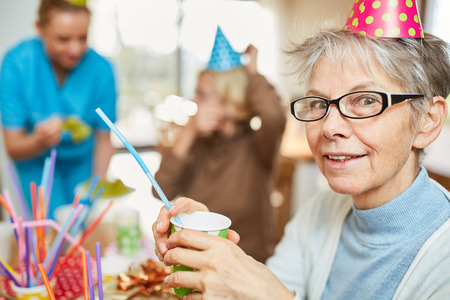 Senior woman in retirement home celebrates birthday together with friends and familyの写真素材