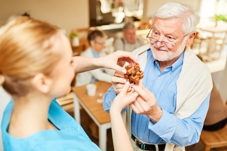 Senior with dementia and caregiver with wooden puzzle as employment in nursing homeの写真素材
