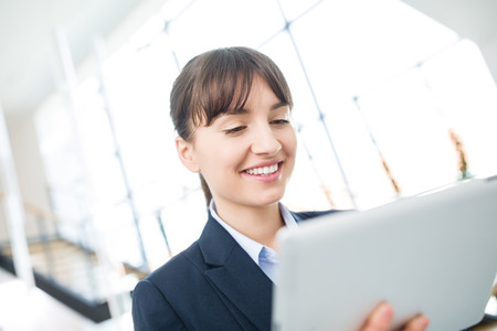Young businesswoman smiling while using digital tablet in officeの写真素材