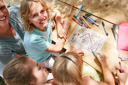 Children paint a home with crayons with their parentsの写真素材