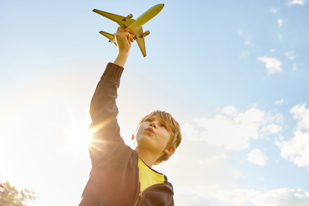 Boy while playing with airplane in hand in the summer in the gardenの写真素材