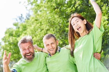Three young people as activists in the green shirt enthusiastically celebrate a successの写真素材