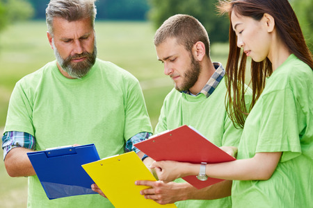 Three people volunteers with clipboard plan together a environmental protection projectの写真素材