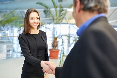 Young business woman says goodbye to a colleague with handshake in airport terminalの写真素材