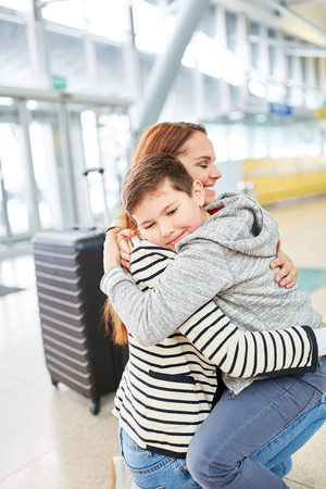 Mother and son embrace each other happily when they meet again after their vacation at the airportの写真素材