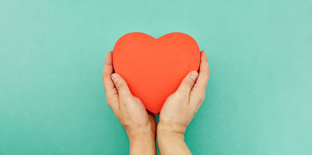 Hands hold red heart as love and care for the elderlyの写真素材