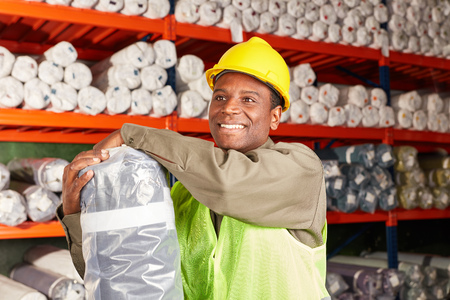 Young man as a logistics apprentice in training with delivery in the carpet warehouse
