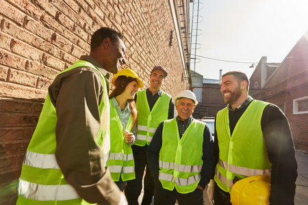 Logistics workers group as a team in a break while small talk in front of a factoryの写真素材