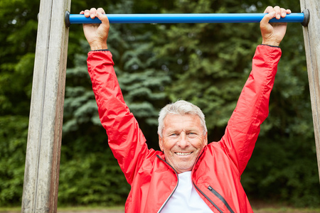 Sporty senior man on the trim you parade makes a chin-upの写真素材