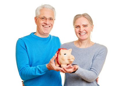 Happy senior couple together saves money in piggy bankの写真素材