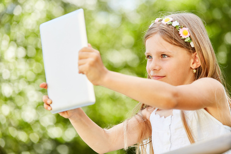 Girl is holding a tablet and taking a selfie for the social mediaの写真素材