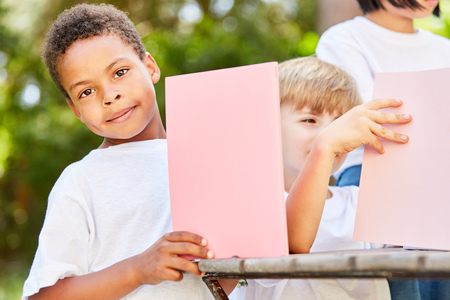 Boy in kindergarten is tinkering with paper or craft carton in the gardenの写真素材
