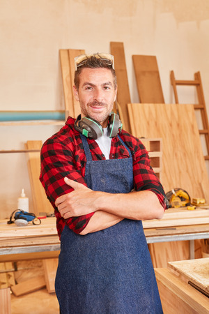 Man as a satisfied carpenter with crossed arms in his workshopの写真素材