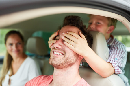 Son keeps his father in the car at the wheel of the eyes on the trip on vacation
