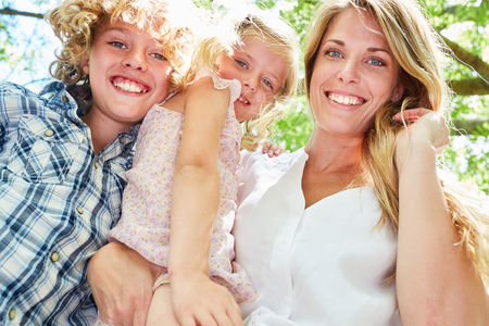 Happy mother with two sibling kids in the sunshine in the nature