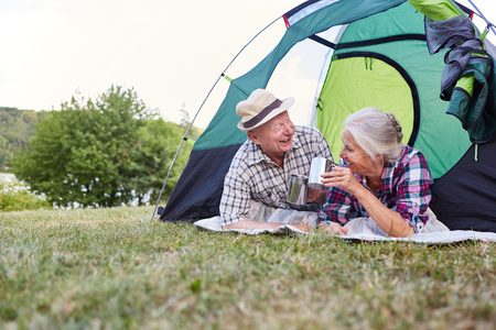 Happy senior couple camping in nature together drinking a cup of coffeeの写真素材