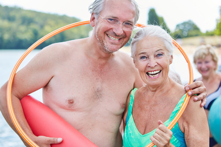 Laughing vital senior couple in summer vacation with a hoop and yoga matの写真素材